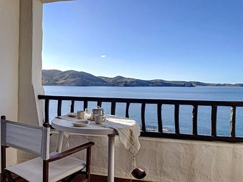 een tafel en stoel op een balkon met uitzicht op het water bij P98 - Bonito apartamento sobre el mar in Fornells