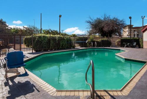una piscina con una sedia blu in un cortile di HomeTowne Studios by Red Roof San Antonio - SeaWorld Northwest a San Antonio