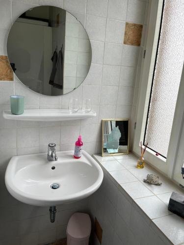 La salle de bains est pourvue d'un lavabo blanc et d'un miroir. dans l'établissement Hermina, à Cochem