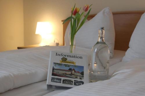 a bottle of information on a bed with a book and flowers at Marienhof in Unterkirchbach