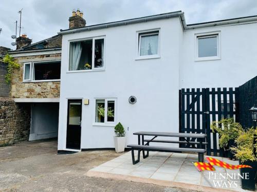 a white house with a picnic bench in front of it at The Spotty - Homely Stay in a Former Inn in Haltwhistle