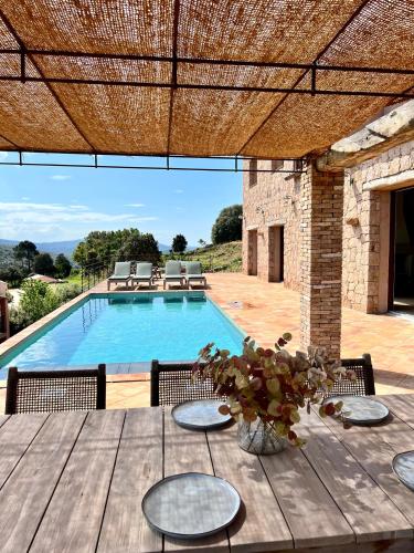 a patio with a table and a swimming pool at Les Demeures de Piana in Piana