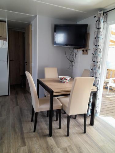 d'une table à manger avec des chaises et une télévision murale. dans l'établissement Mobilhome 422 3ch/1 sdb camping 4* La Réserve SIBLU Gastes, à Gastes