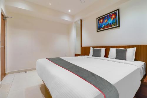 a bedroom with a white bed and a painting on the wall at Super Townhouse 1144 Hotel RCC 7 Lamps in Alipur