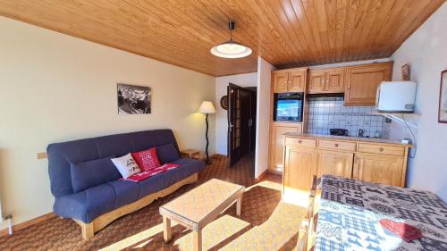 un salon avec un canapé bleu et une cuisine dans l'établissement Eperon 2 - F4 - Studio lumineux - 6 pers, à Les Deux Alpes