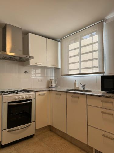 uma cozinha com armários brancos e um forno com placa de fogão em DEPARTAMENTO Céntrico MENDOZA em Mendoza