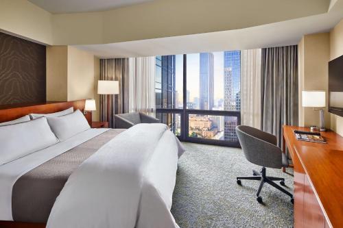 ein Hotelzimmer mit einem großen Bett und einem Schreibtisch in der Unterkunft The Westin Bonaventure Hotel & Suites, Los Angeles in Los Angeles