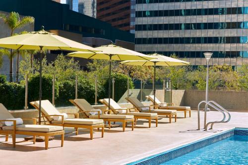 una fila de sillas y sombrillas junto a una piscina en The Westin Bonaventure Hotel & Suites, Los Angeles en Los Ángeles