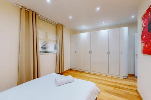 a bedroom with a white bed and white cabinets at Beautiful 2Bed Apartment with lift in Kensington in London