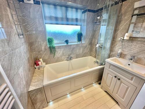 a bathroom with a tub and a sink and a window at Sea View Three Bed Detached Home - With Parking - Next to Beach! in Bournemouth