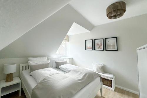 a white bedroom with a bed and a window at Techts Landhus Birkenallee in Timmendorfer Strand