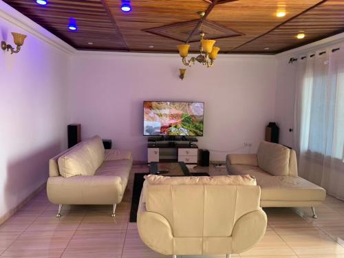a living room with two couches and a flat screen tv at RESIDENCE LA VARENNE, DSCHANG in Dschang
