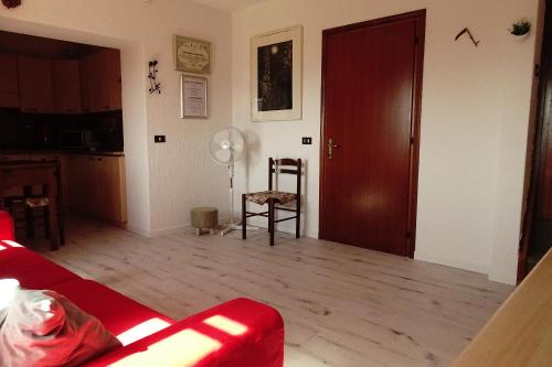 een woonkamer met een rode bank en een houten vloer bij La casetta di Elsa in Cesiomaggiore