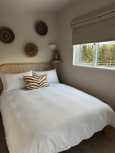 a bedroom with a large white bed with a window at The Pod @ Essex House in Bronington