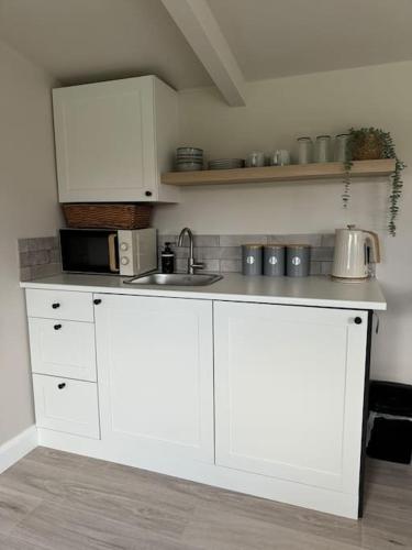 a kitchen with white cabinets and a sink at The Pod @ Essex House in Bronington