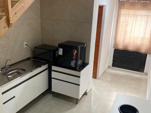 uma pequena cozinha com um micro-ondas e um lavatório em Loft BR 282 em Lages