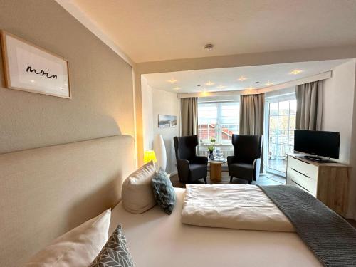 ein Hotelzimmer mit einem Bett, einem Schreibtisch und Stühlen in der Unterkunft Landhotel Bauernstuben in Neuharlingersiel