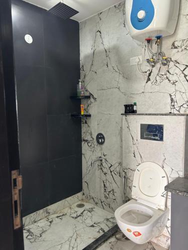 a bathroom with a toilet and a marble wall at Shiv dham in New Delhi