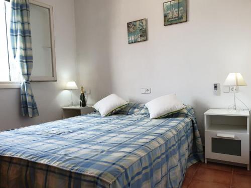 a bedroom with a bed with a blue plaid blanket at F76. Vistas al mar en Fornells! in Fornells