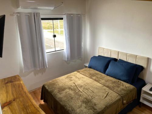 a bedroom with a bed with blue pillows and a window at Loft BR 282 in Lages