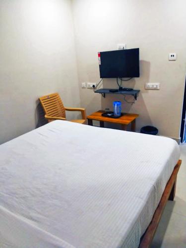 a bedroom with a white bed and a television at MS Comforts Mahadevapura in Bangalore