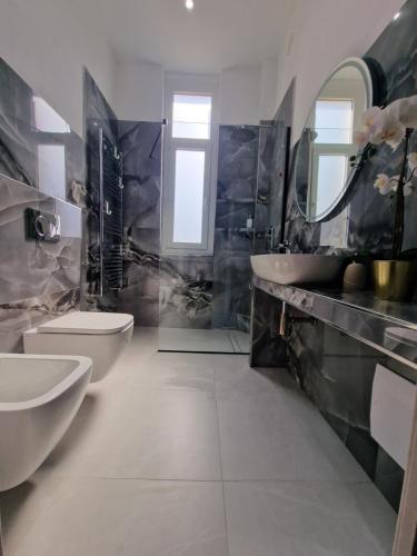 een badkamer met 2 wastafels, een toilet en een spiegel bij La casa della stazione in La Spezia