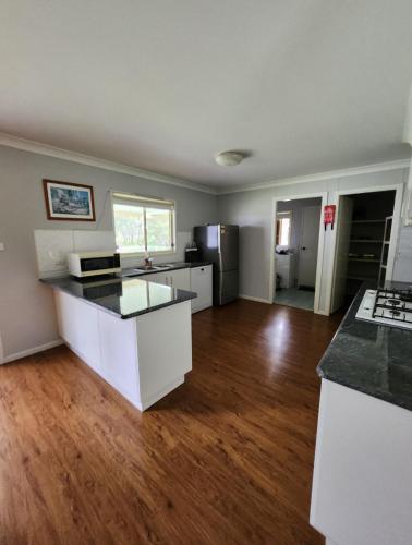 a large kitchen with white cabinets and a hard wood floor at Kollannoor Homestead in Mitchells Island
