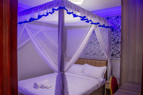 a bedroom with a canopy bed with towels on it at Equine Hotel in Ruiru