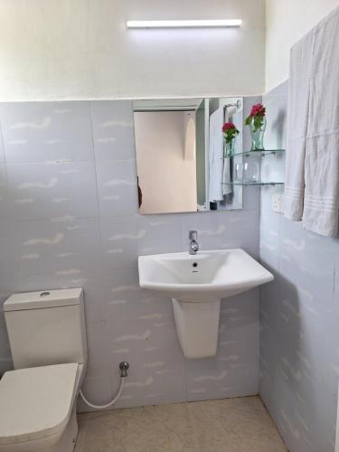 a white bathroom with a sink and a toilet at Baden Beach in Kalkudah