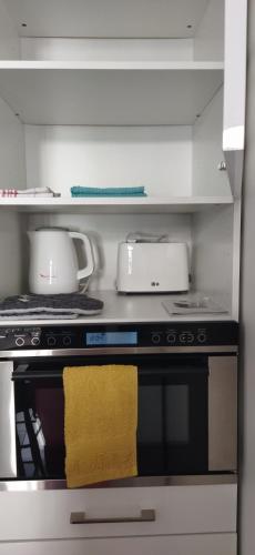 - une cuisine avec une cuisinière et une serviette jaune dans l'établissement Super studio, proche centre ville, à Rochefort