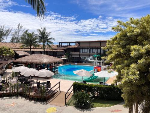 uma piscina com guarda-sóis e um resort em Hotel Vilarejo Praia em Rio das Ostras