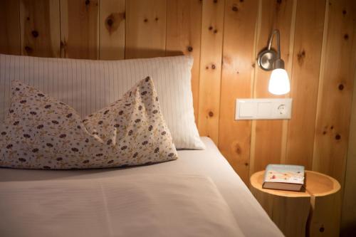 a bed with a pillow and a table with a book at Schneckenhaus Dachstein West in Russbach am Pass Gschütt