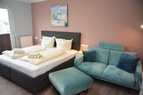 a bedroom with a bed and a couch and a chair at Strandhotel 21 in Laboe