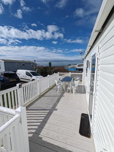 a deck with a table and chairs on a house at ACCESSIBLE FRIENDLY MODERN Family Caravan Littlesea Haven Weymouth in Weymouth