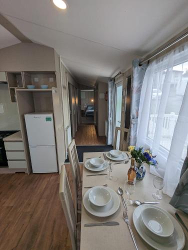 a dining room table with plates and glasses on it at ACCESSIBLE FRIENDLY MODERN Family Caravan Littlesea Haven Weymouth in Weymouth
