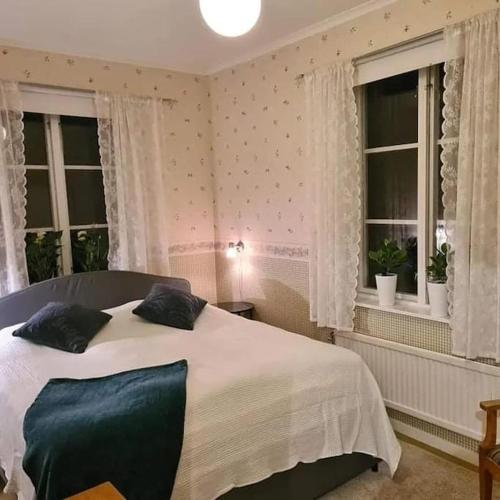 a bedroom with a large bed with two windows at Sörgården - hyr hela gården! (2-35 personer.) in Köping
