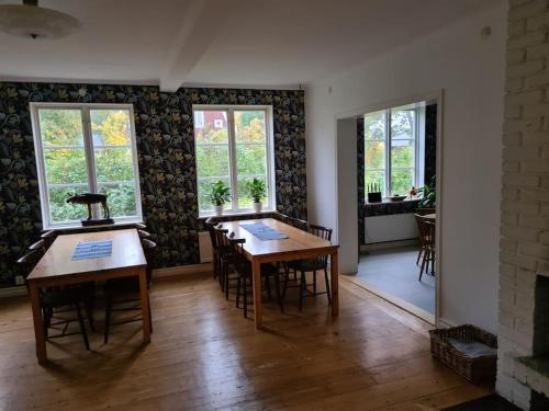 een eetkamer met tafels, stoelen en ramen bij Sörgården - hyr hela gården! (2-35 personer.) in Köping