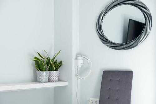 a mirror hanging on a wall next to a plant at DIIO Suites in Ermoupoli