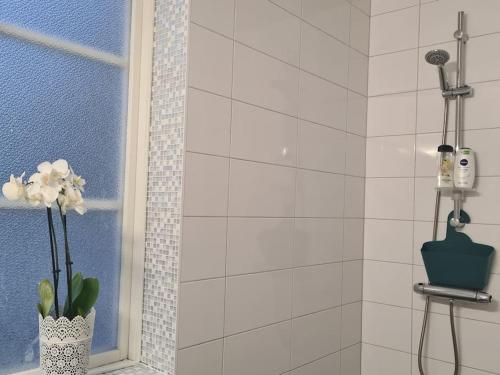 een badkamer met een douche en een vaas met bloemen bij Sörgården - hyr hela gården! (2-35 personer.) in Köping