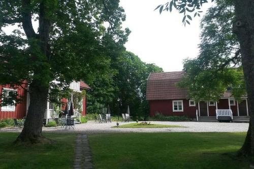 a red building with a red house and a tree at Sörgården - hyr hela gården! (2-35 personer.) in Köping