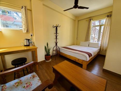 um pequeno quarto com uma cama e uma mesa em santoshi guest house em Pokhara