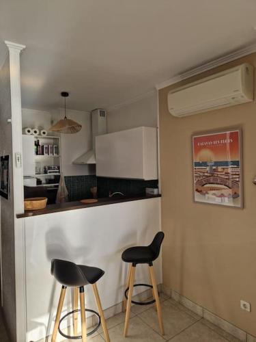 une cuisine avec deux tabourets noirs et un comptoir dans l'établissement Appartement familial T2 vue mer, à Palavas-les-Flots