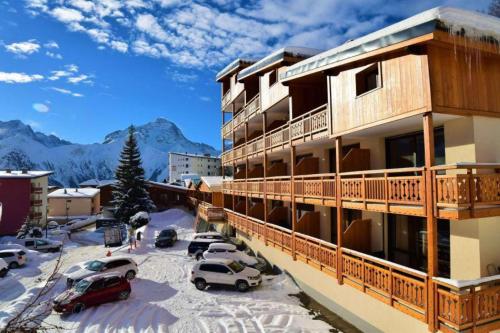 un bâtiment avec des voitures garées dans un parking dans l'établissement Super Venosc - F2 - Appart pied de piste - 6 pers, à Les Deux Alpes