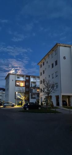 a building with cars parked in a parking lot at Apartmani Iva in Banja Koviljača