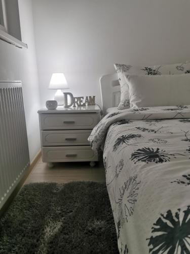 a bedroom with a bed and a dresser with a lamp at Apartmani Iva in Banja Koviljača