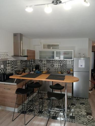 - une cuisine avec une table et des tabourets en bois dans l'établissement Les Arcades, T2 en hypercentre, à La Rochelle