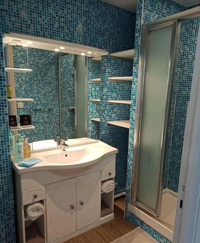 une salle de bain carrelée bleue avec un lavabo et une douche dans l'établissement T1 Centre Proche du Port et des Plages Garage Climatisation Wifi, à Carry-le-Rouet