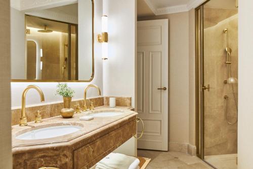 uma casa de banho com 2 lavatórios, um espelho e um chuveiro em The Westin Palace, Madrid em Madrid