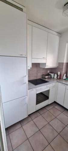 a kitchen with white cabinets and a tile floor at Asima in Montreux