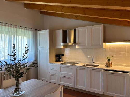 a kitchen with white cabinets and a vase on a table at Residence La Colombera in Riva del Garda